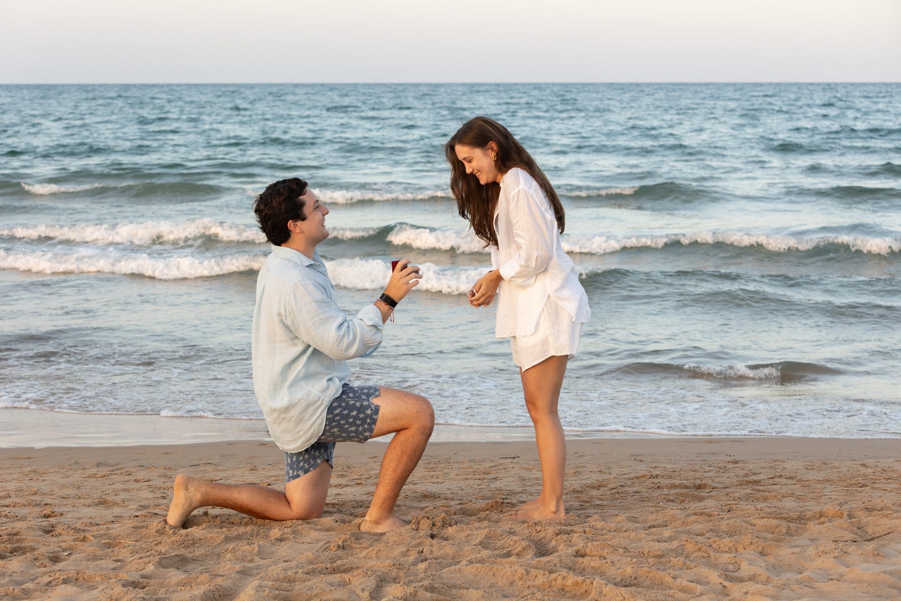 Santiago arrodillado frente a Bárbara en la playa